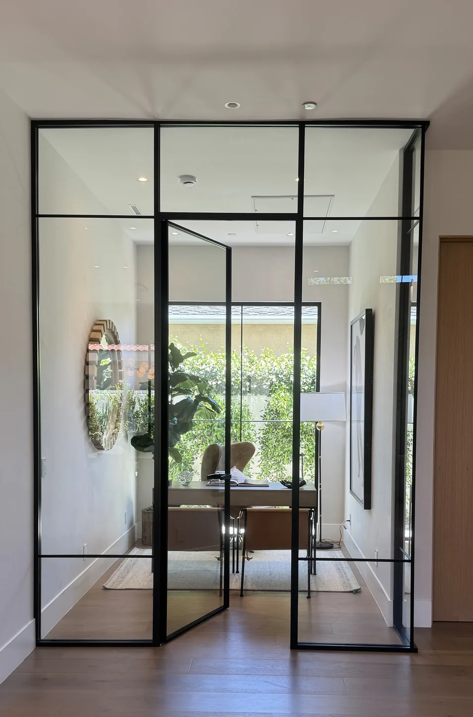 Aeres corner glass partition enclosing a home office, pivot door ajar